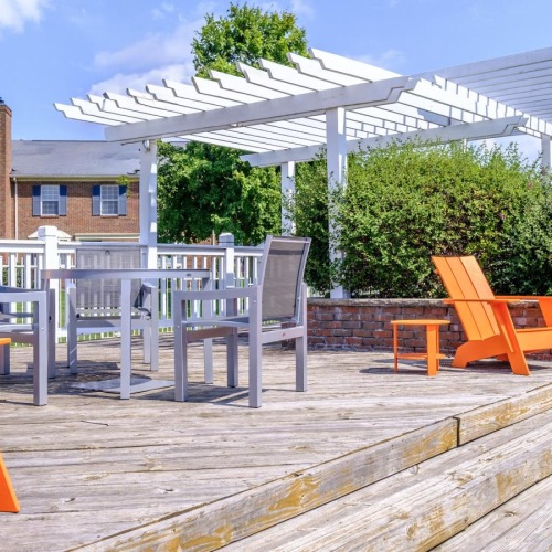 a deck with tables, chairs, and orange Adirondack chairs