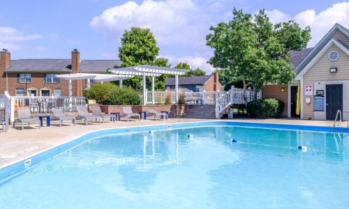 a large swimming pool with poolside lounge chairs and a grilling area